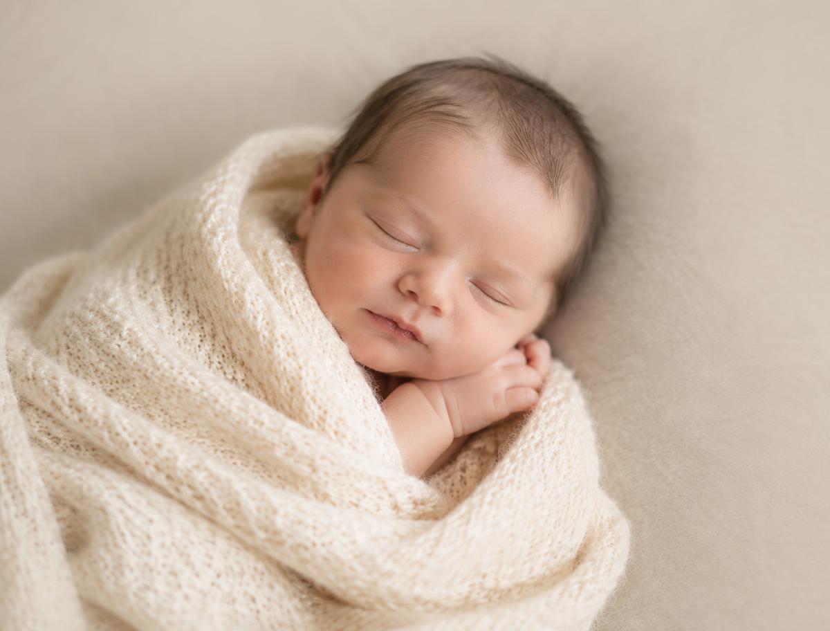 Pasgeboren baby in een crème gebreide doek