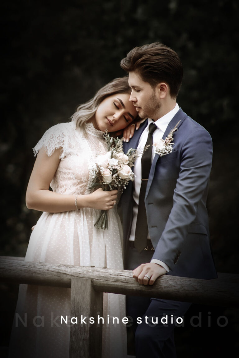 Een bruidspaard omhelst elkaar teder bij een houten hekwerk in een romantische, natuurlijke omgeving.